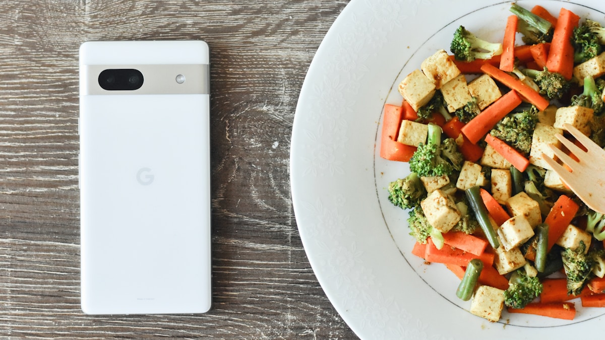 Aplicativo de dieta aberto no celular ao lado de um prato de comida