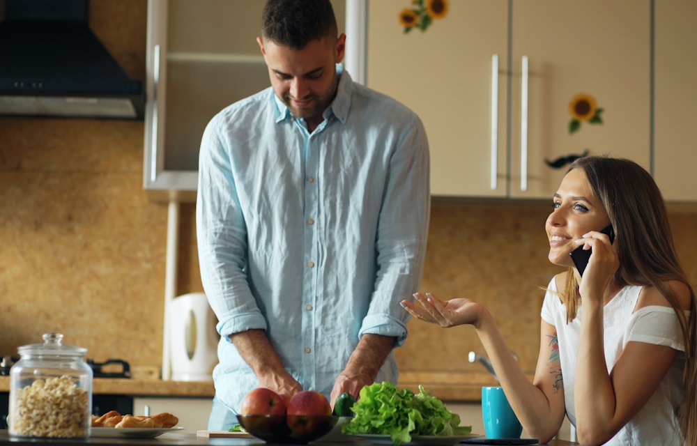 Casal usando o aplicativo de dieta na cozinha durante o preparo da refeição