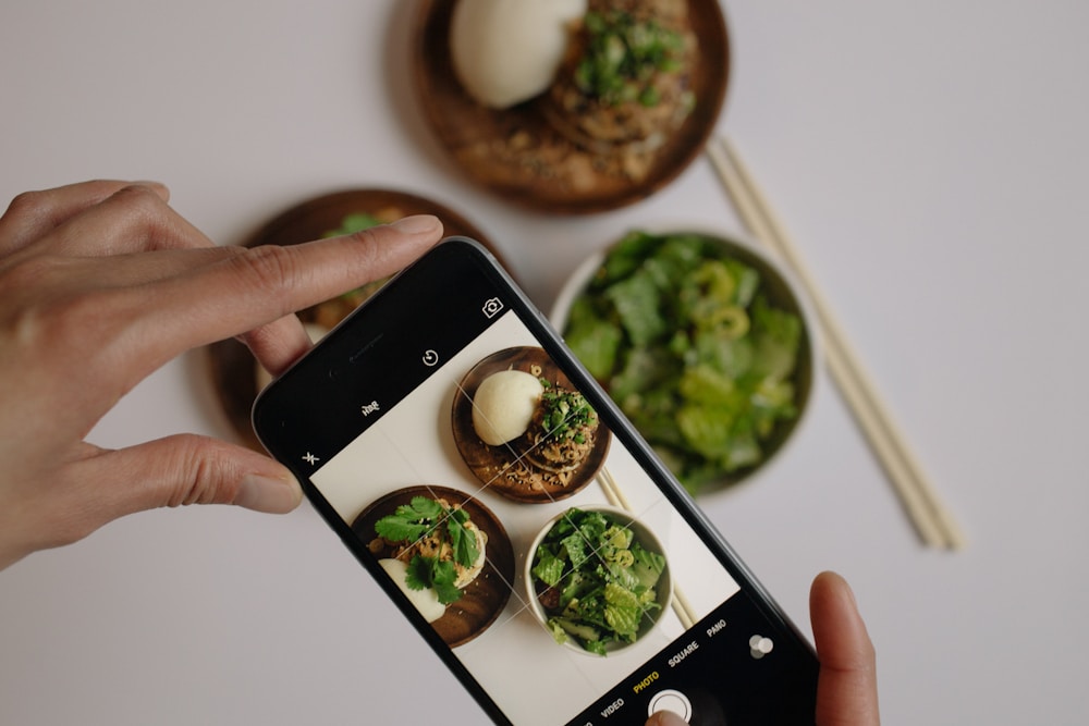 Pessoa fotografando vegetais com o celular para registrar no app